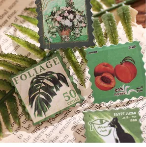 Macro detail of vintage stamp stickers with foliage and fruit motifs for DIY scrapbooking.