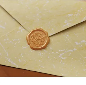Detail eines goldenen Siegellacks mit „For You“-Prägung auf einem gelben Briefumschlag.