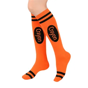 Close-up view of orange crayon-themed knee-high socks featuring black stripes and text