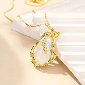 Détail d'un collier pendentif en perle baroque avec un motif d'épi de blé doré élégant