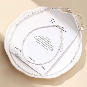 Macro detail of faceted white howlite bead necklace set on elegant display with card