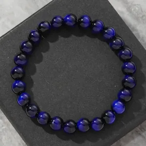 Close-up of blue tiger eye beaded bracelet with shimmering chatoyancy on black gift box