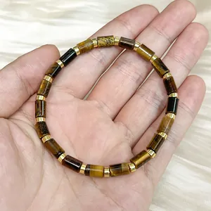 Close-up of natural cylindrical tiger eye stone bracelet with gold spacer beads on hand