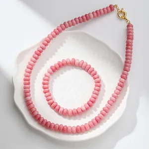 Conjunto de collar y pulsera de cuentas de cristal craquelado rosa en plato blanco