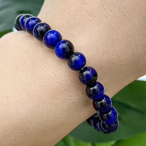 Close-up detail showing shimmering blue cat's eye glass beads on a stylish beaded bracelet