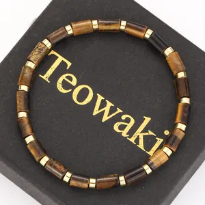 Macro view of natural yellow tiger eye cylindrical beads and gold spacers on a black box.