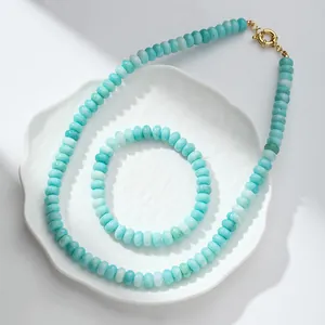 Primer plano de un conjunto de collar y pulsera de cristal azul craquelado en plato blanco.