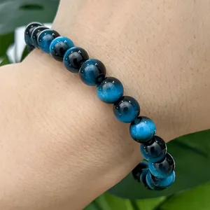 Macro view of chatoyant blue glass tiger eye beads on a minimalist beaded bracelet