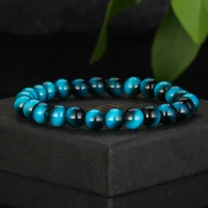 Detailed close-up view of a blue tiger eye glass beaded bracelet on a black gift box.