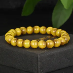 Detail shot of yellow faux tiger eye glass beaded bracelet on black box