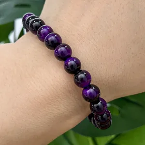 Close-up of purple cat eye glass beaded bracelet worn on wrist with leaf background