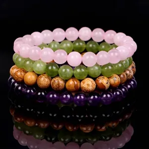 Stacked natural gemstone bead bracelets in pink, green, brown, and purple tones
