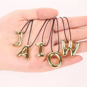 Close-up of 20mm golden copper alphabet letter pendants for DIY jewelry making