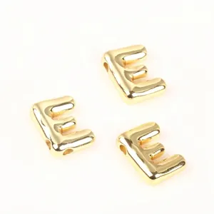 Macro view of polished 20mm gold copper letter E beads for DIY jewelry making crafts