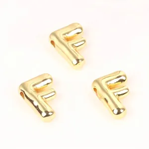 Close-up of shiny gold-plated copper letter F beads for DIY jewelry making