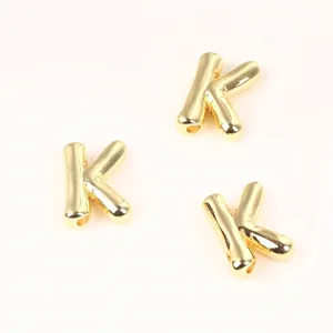 Detailed view of polished 20mm golden copper letter K beads for DIY jewelry making