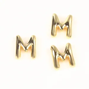 Detail shot of three puffy gold-toned copper letter M beads for DIY jewelry making