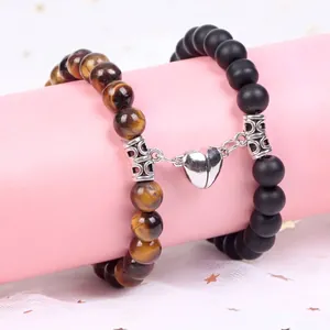 Detail view of magnetic heart clasp joining tiger eye and black matte bead bracelets.