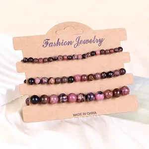 Nahaufnahme von pink Zebra- und schwarzen Steinperlen-Armbändern auf brauner Karte