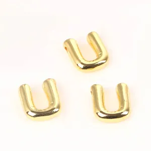 Detailed macro view of 20mm golden copper letter U beads for DIY jewelry making.