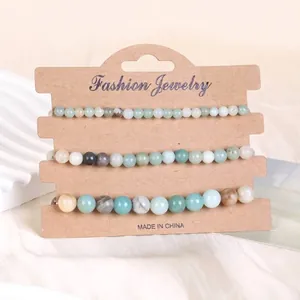 Dreiteiliges Set aus Natursteinperlen-Armbändern auf einer braunen Kraftpapier-Schmuckkarte