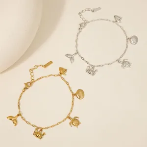 Two stainless steel bracelets with sea charms like turtles and shells on a beige surface.