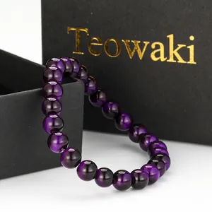 Detail shot of a purple cat eye glass beaded bracelet on a premium black gift box