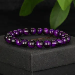 Detailed view of a purple cat eye glass beaded bracelet resting on a black jewelry box