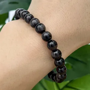 Close-up detail of black round glass tiger eye beads stretch bracelet worn on a wrist