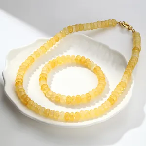 Detalle de collar y pulsera de cristal craquelado amarillo en un plato de concha blanca.