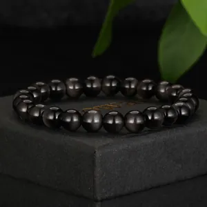 Macro detail of glossy black glass beaded bracelet showing elegant cat-eye luster