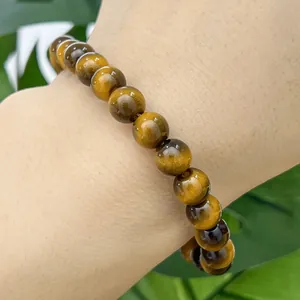 Close-up view of imitation tiger eye glass beaded bracelet worn on wrist for men and women