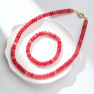 Vista detallada de un conjunto de collar y pulsera de cuentas de cristal rojo en un plato