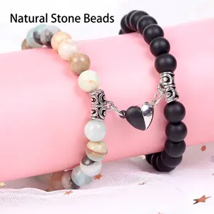 Detail of magnetic heart charm connecting couple's natural stone bead bracelets
