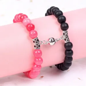 Close-up of magnetic ball clasp joining pink and black stone bead bracelets for couples
