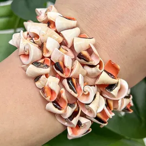 Detailed view of a handmade natural conch and red mouth shell bracelet on a wrist