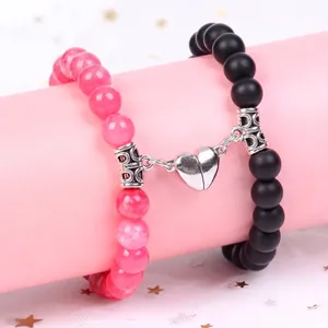 Close-up of magnetic heart charm connecting pink and black beaded couple bracelets