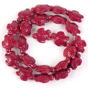 Detailed view of synthetic turquoise beads carved in red turtle shapes for DIY projects