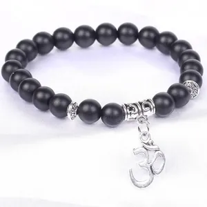 Detailed view of matte black natural stone bead bracelet with silver Om charm pendant