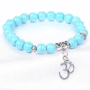 Macro view of blue turquoise beads and silver Om symbol charm on bracelet