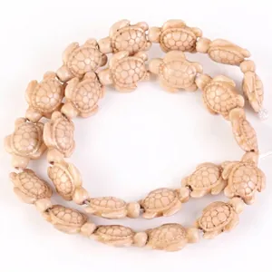 Close-up detail of carved beige synthetic stone turtle beads for DIY jewelry accessories