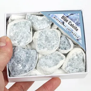 Primo piano di campioni di calcite blu grezza in una scatola regalo bianca in mano.