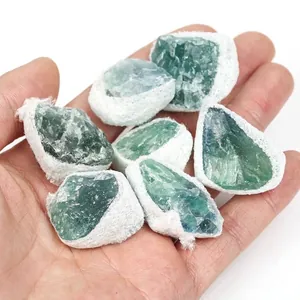 Natural raw green fluorite mineral crystals held in hand with white foam netting