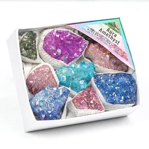 Gros plan de grappes de cristaux d'améthyste aura colorés dans un coffret cadeau blanc chic