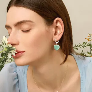 Vue détaillée d'une boucle d'oreille créole argentée avec pendentif cœur vert clair