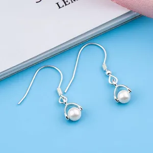 Detailweergave van zilverkleurige vishaak oorbellen met een elegante witte parelhanger.