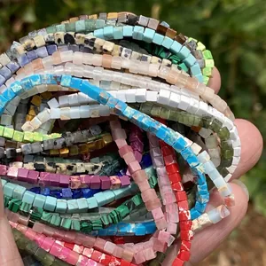 Detailed macro view of colorful 2x2mm natural stone square spacer beads in hand