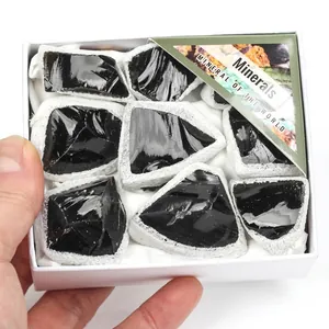 Primer plano de piedras minerales de obsidiana negra natural en una caja de regalo