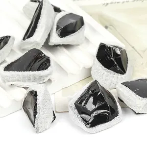 Primer plano de piedras naturales de obsidiana negra cruda con envoltura blanca