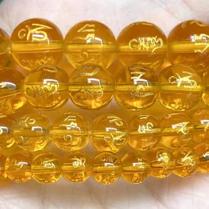 Macro detail of yellow translucent beads with engraved gold mantra symbols for jewelry DIY